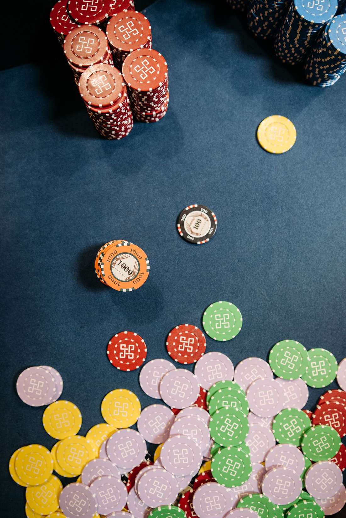 Keping taruhan berwarna tersusun di atas meja kasino